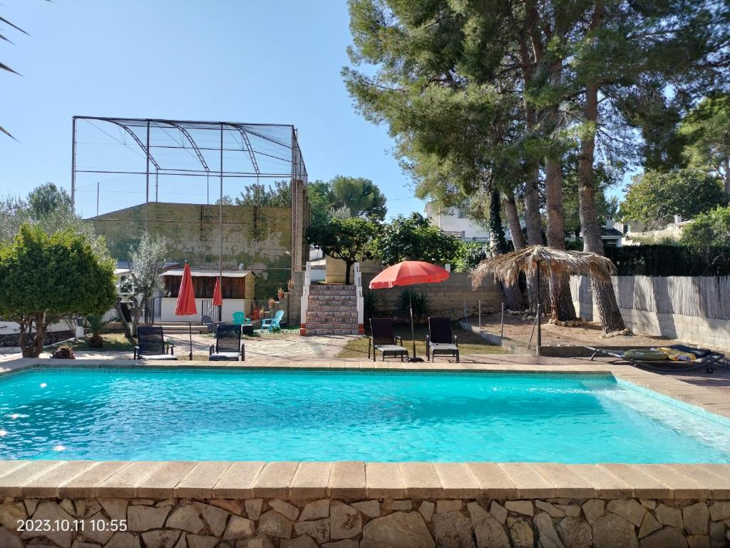 een zwembad met stoelen en parasols in een tuin bij Casa Mas Montanas vakantiehuis met zwembad Max 10 pers Vlakbij Valencia in Godelleta