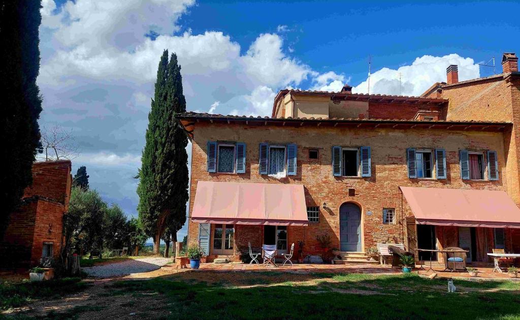 una vieja casa de ladrillo con un toldo rosa en Casa Ezio Marchi - Tre spaziose suite, en Bettolle
