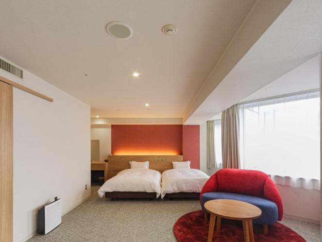 1 dormitorio con 1 cama y 1 silla roja en Awa Kanko Hotel en Tokushima