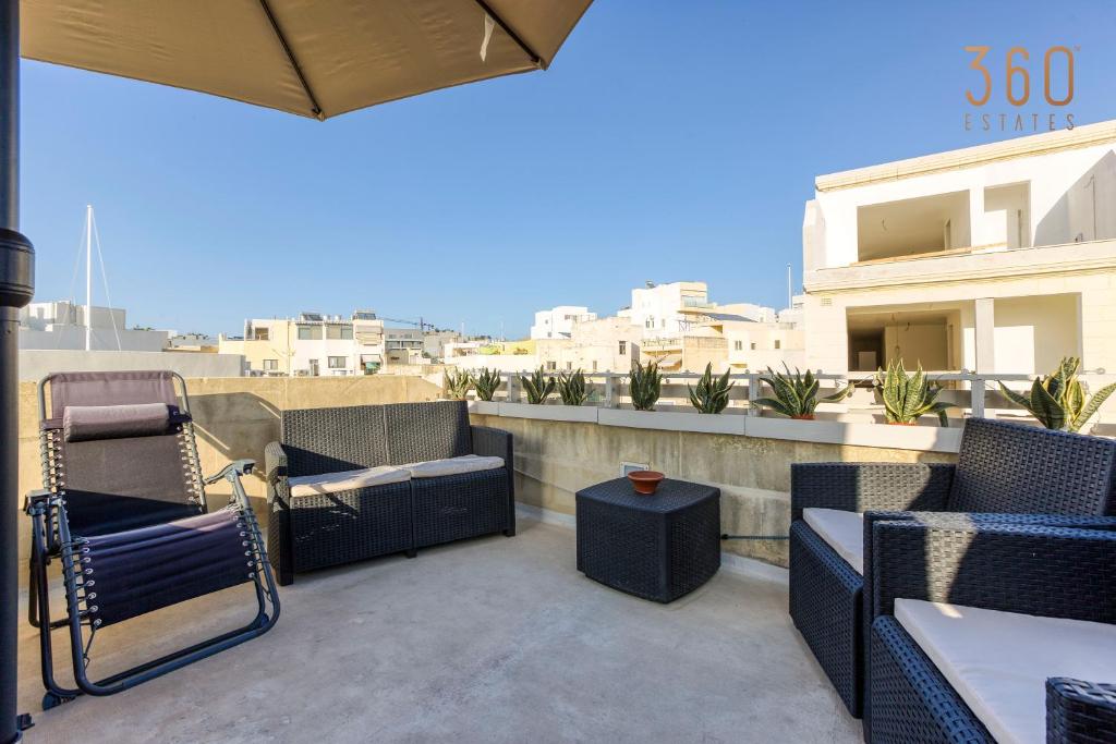 a patio with chairs and tables on a balcony at Authentic 2BR House of Character with Terrace by 360 Estates in Naxxar