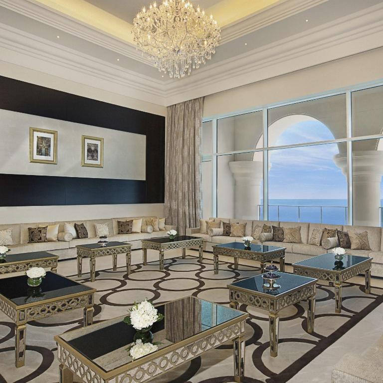 a living room with couches and tables and a chandelier at Waldorf Astoria Dubai Palm Jumeirah in Dubai