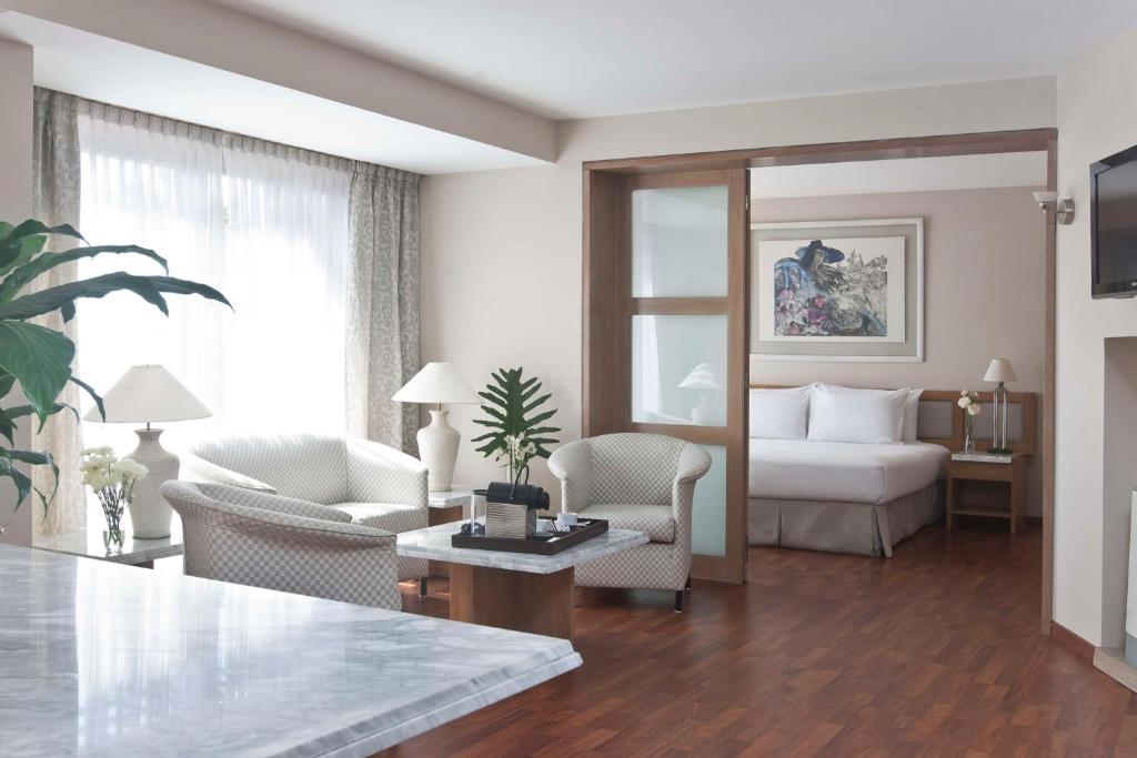 uma sala de estar com uma cama, uma mesa e cadeiras em NH Córdoba Urbano em Córdoba