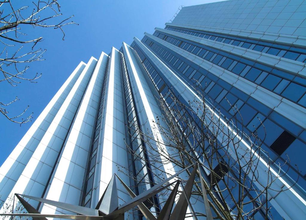 un edificio de cristal alto con un cielo azul en el fondo en Congress Hotel Chemnitz, en Chemnitz