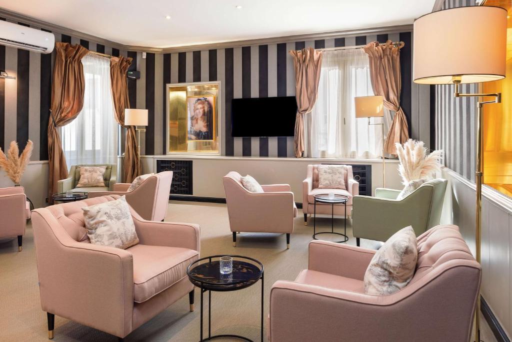 a living room with couches and chairs and a television at Best Western Plus Hôtel Brice Garden Nice in Nice