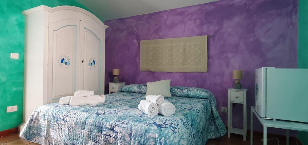 ein Schlafzimmer mit lila Wänden und ein Bett mit Handtüchern drauf in der Unterkunft Da Ida in Bosa