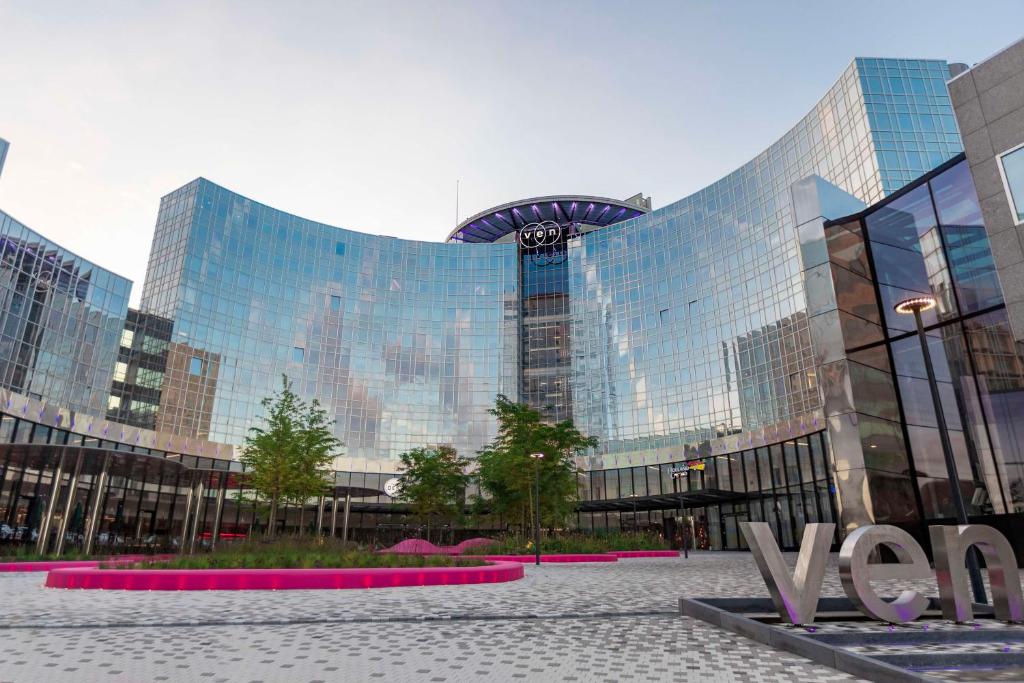 un grand bâtiment en verre avec un panneau devant lui dans l'établissement Park Inn by Radisson Amsterdam City West, à Amsterdam