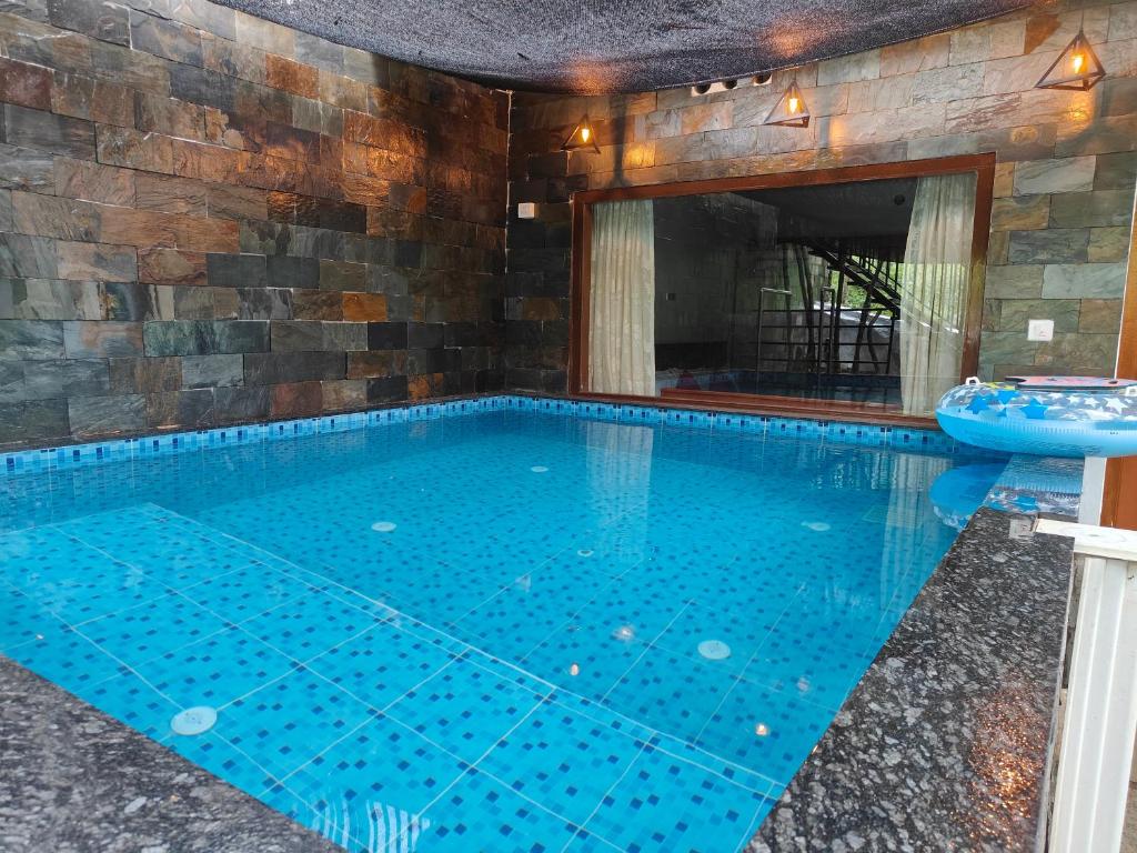 a swimming pool in a house with a stone wall at Agasthya Private Pool & Park villa in Sultan Bathery