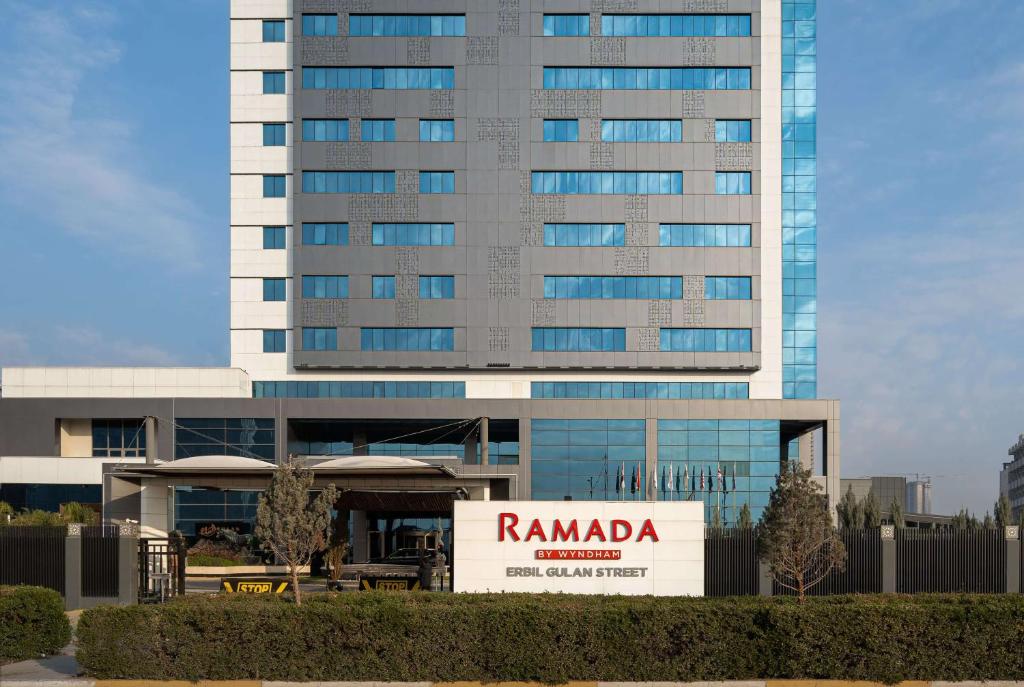 a tall building with aania sign in front of it at Ramada by Wyndham Erbil Gulan Street in Erbil