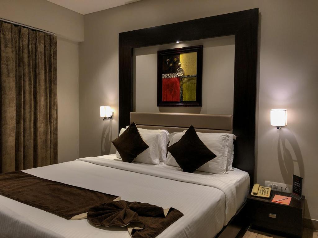 a hotel room with a bed with white sheets and pillows at Hotel Virgo Sumeru in Bhavnagar
