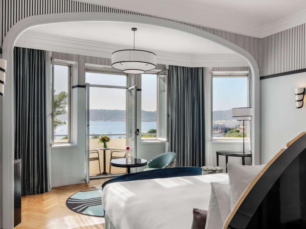 a hotel room with a large bed and windows at Le 1932 Hotel & Spa Cap d'Antibes - MGallery in Juan-les-Pins