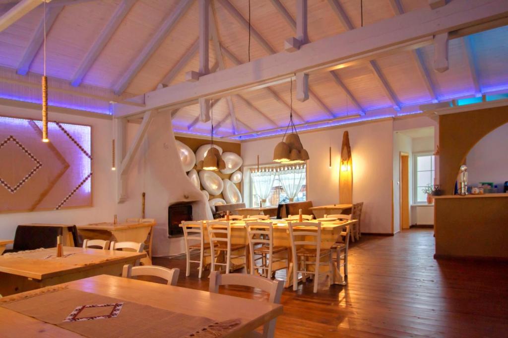 un restaurante con mesas y sillas de madera e iluminación púrpura en Fexada Home en Vama