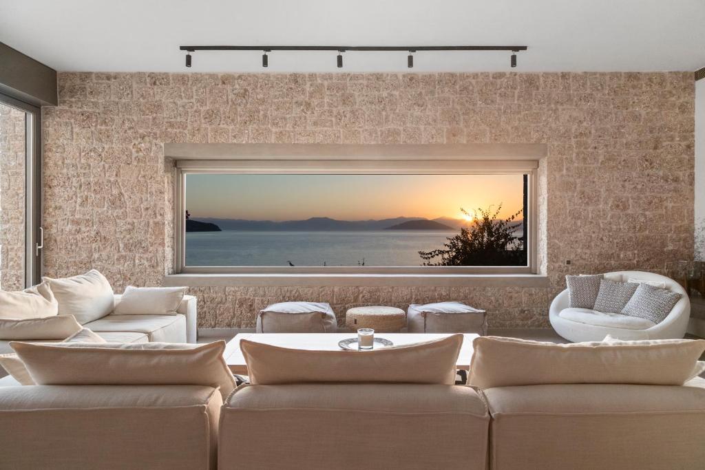 a living room with a couch and a large window at Villa Olea - Luxury Villa with Swimming pool, Tennis court & Beach Volley in Koilás