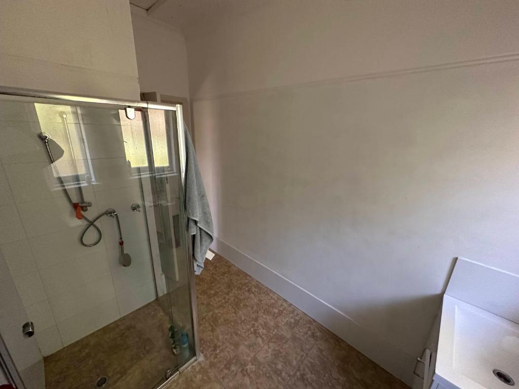uma casa de banho com um chuveiro e uma cabina de duche em vidro. em Chimu Home-Hostel em Perth