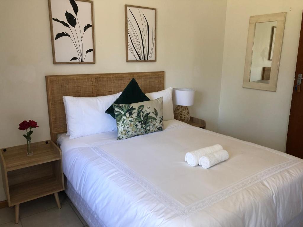 1 dormitorio con 1 cama blanca y 2 toallas en Bluebanana Lodge, en Mthatha