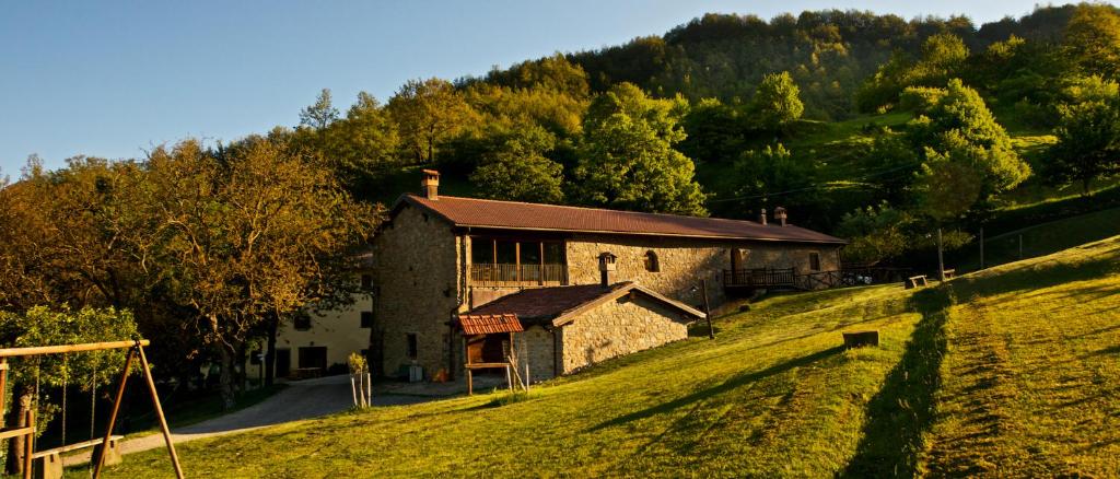 a building on a hill next to a grassy field at Agriturismo Il Passeggere in Bruscoli