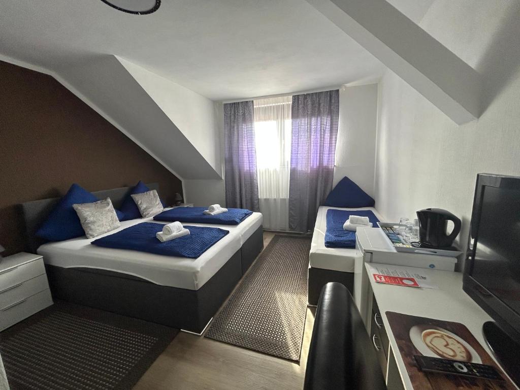 Habitación pequeña con 2 camas y TV. en Hotel Hasselberg, en Kaiserslautern
