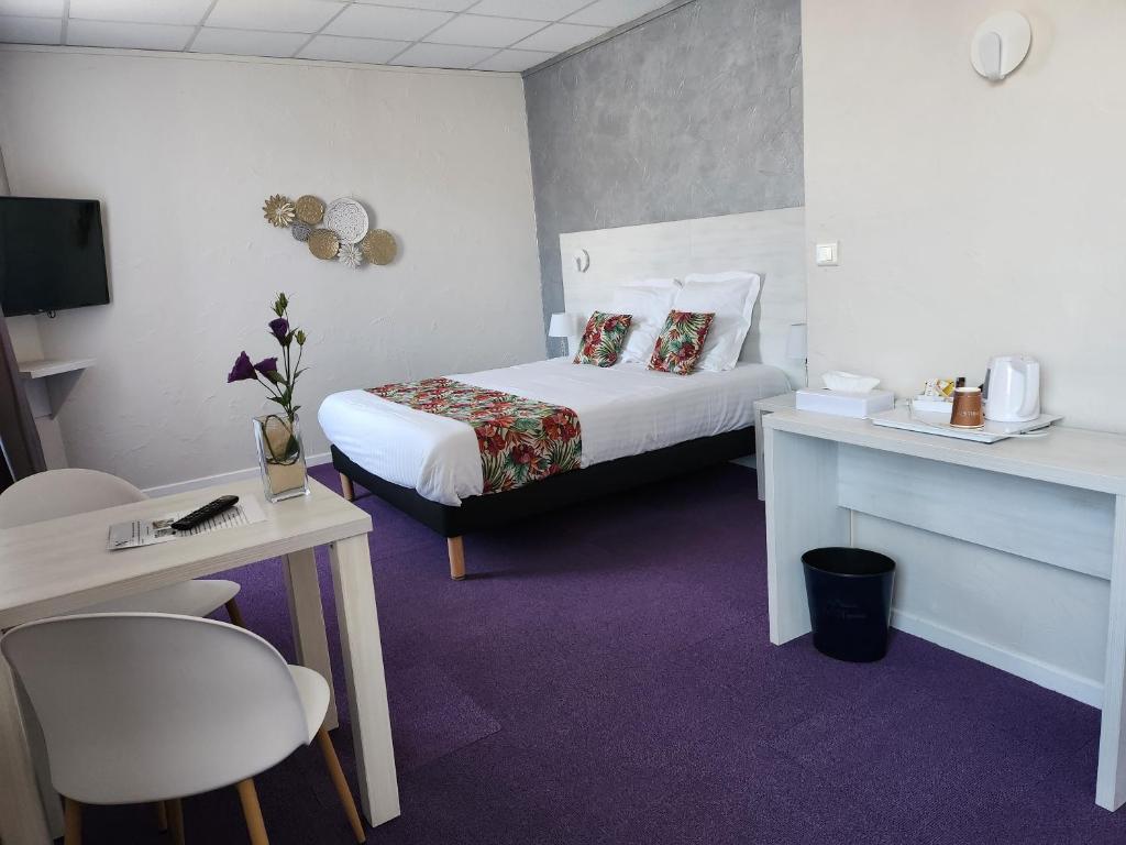 een hotelkamer met een bed en een tafel en stoelen bij Hotel Des Négociants in Lamastre