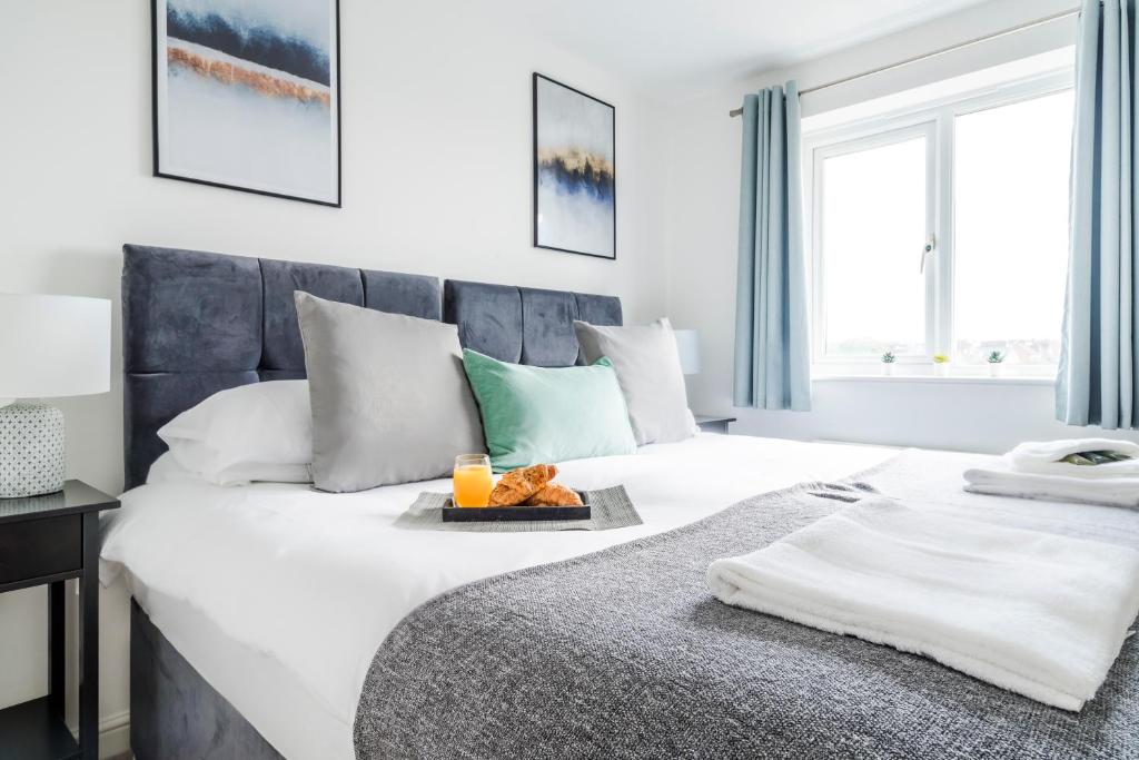 a bedroom with a large bed with a tray of food on it at Robinson House I A Calm & Executive 3BR House w Garden & Parking I eco-Short Term Let by SILVA in Hardingstone