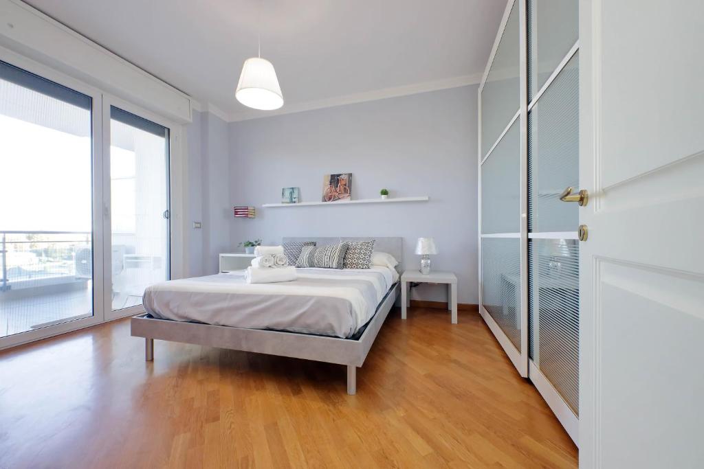a white bedroom with a bed and a large window at Lusso Con Vista - Elegante e Luminoso con Self Check-in, Vicino All'Aeroporto in Fiumicino