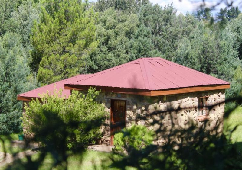 un pequeño edificio con techo rojo frente a un bosque en Khutsong Lodge, 