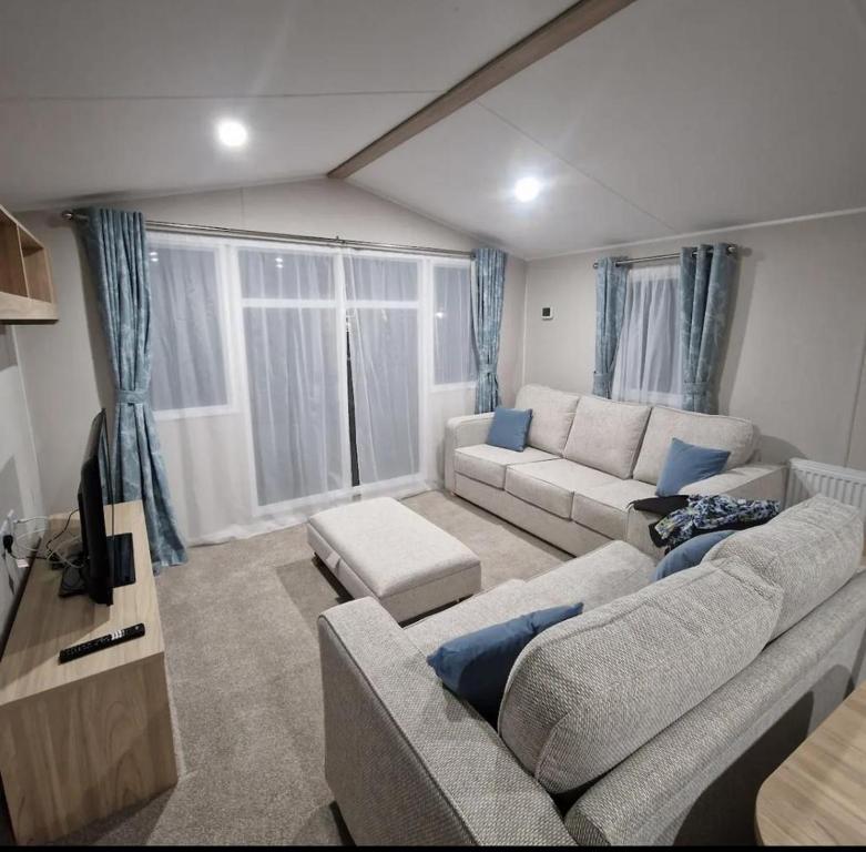 a living room with a couch and a tv at Luxuary Static Caravan Sleeps 6 Coopers Beach - Luxurious Get Away in East Mersea