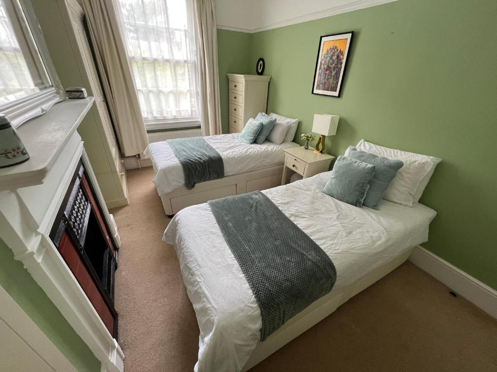 2 camas en una habitación con paredes verdes en The Victorian Rooms, en Surbiton
