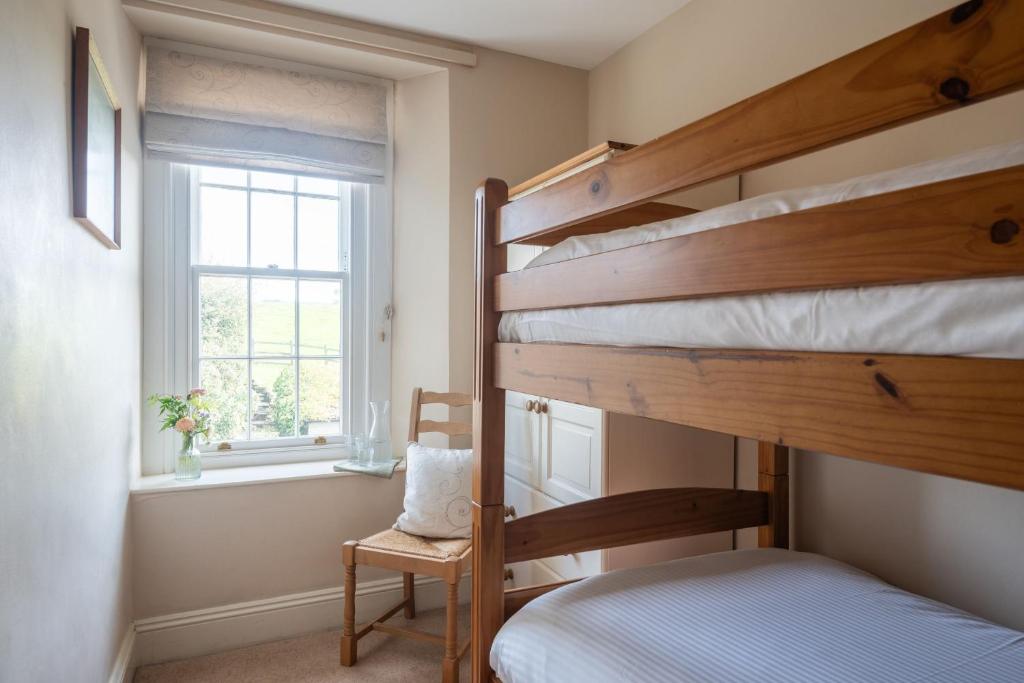 a bedroom with two bunk beds and a window at Rosehip Cottage in Holbeton