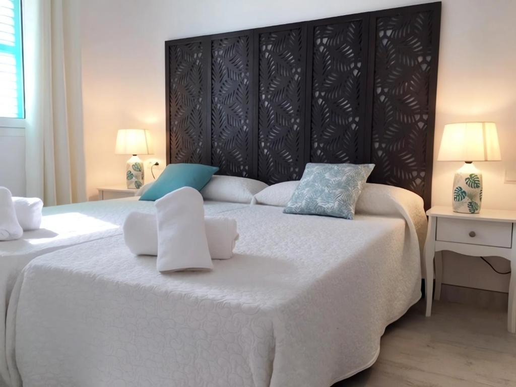 una camera da letto con un grande letto bianco con due cuscini di Apartamentos Roca Plana - Formentera Break a Es Pujols