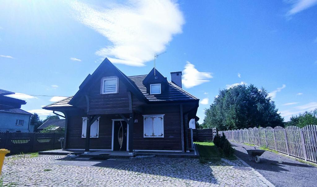 mały brązowy dom siedzący obok płotu w obiekcie Willa Myśliwska w mieście Chocznia