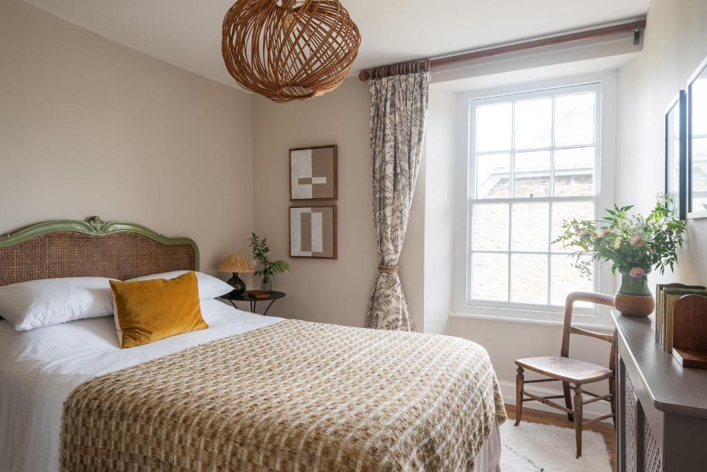 a bedroom with a bed and a window at Wild Rose Cottage in Holbeton