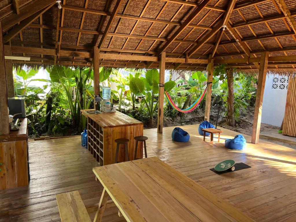 a pavilion with a wooden floor and a table and chairs at Three Little Birds Hostel in General Luna