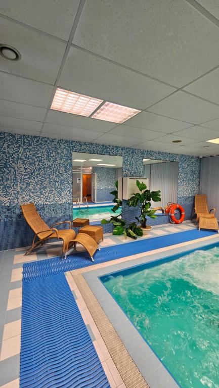 einen Pool in einem Hotelzimmer mit Stühlen und einem Pool in der Unterkunft BEST BALTIC Kaunas in Kaunas