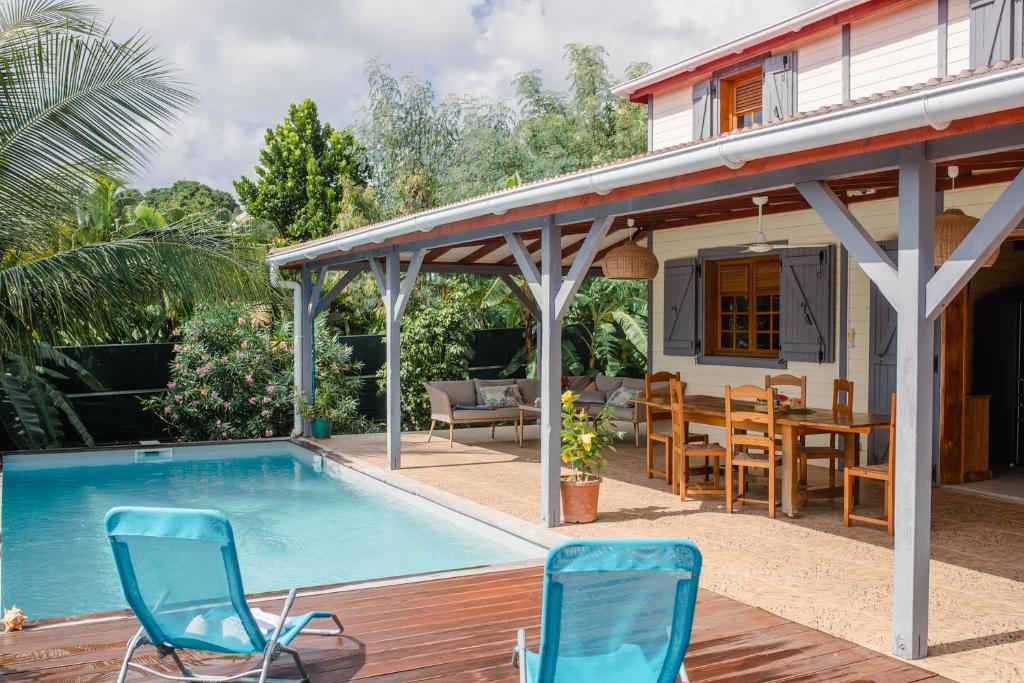 einen Pool mit Stühlen und ein Haus in der Unterkunft Domaine Babwala, villa et bungalow avec piscine dans un superbe jardin tropical #cosy in Saint-Louis