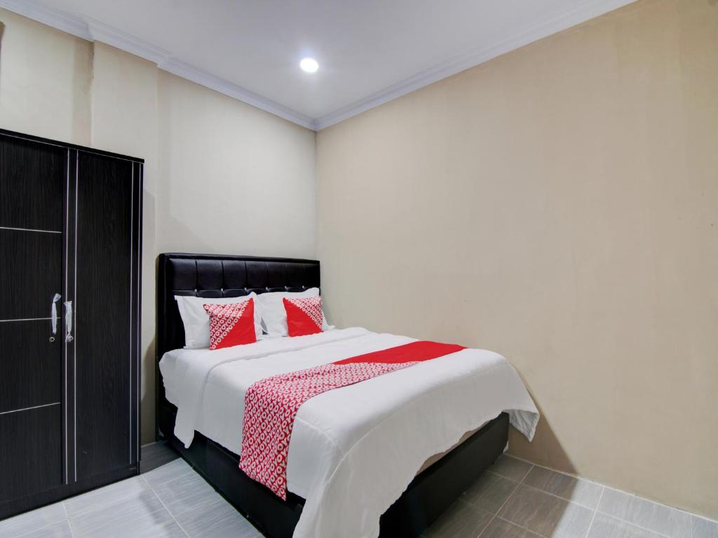 1 dormitorio con 1 cama grande con almohadas rojas en OYO 93087 Wisma Apel Syariah, en Parit