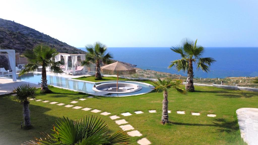 アギア・ペラギアにある"BlueVedere" Sea View Luxury Villaのプール、ヤシの木、海を望むリゾート
