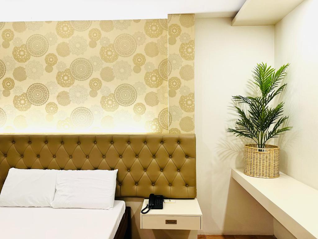 ein Schlafzimmer mit einem Bett und einer Pflanze an der Wand in der Unterkunft Dreaming Forest Hotel - Libjo, Batangas in Batangas City
