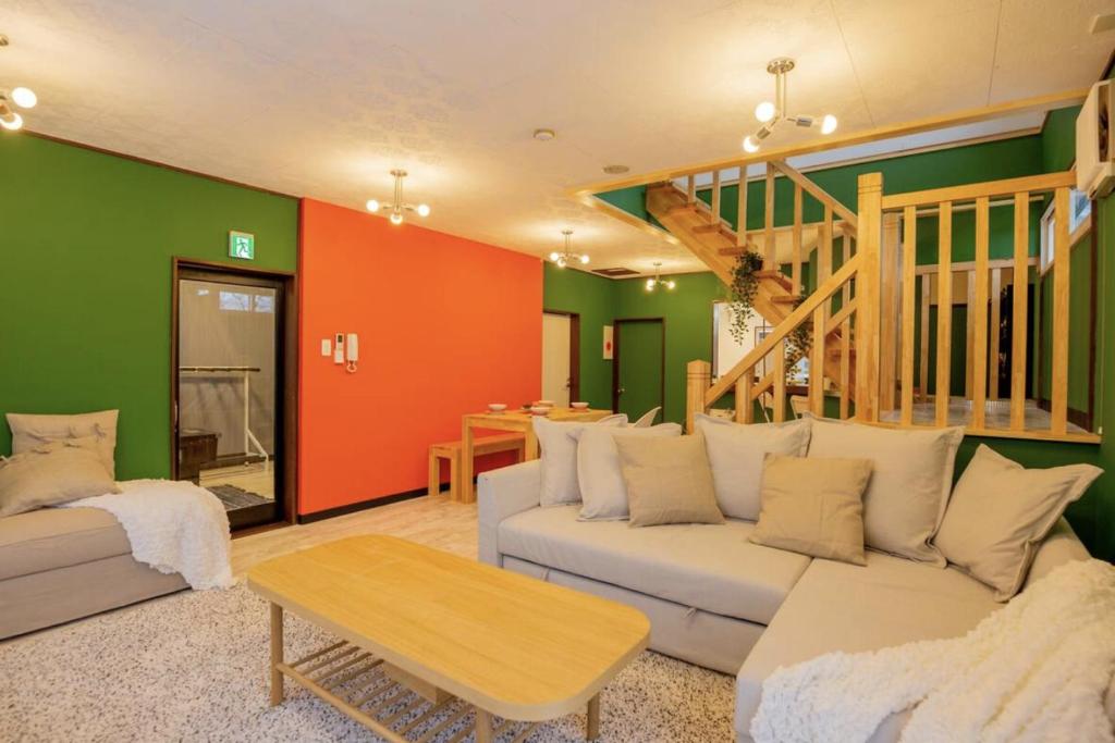 a living room with a white couch and a staircase at Yuzawa Onsen Lodge 1min to LIFT House in Seki