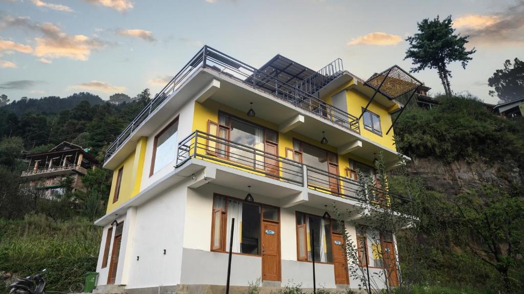 a yellow and white house on top of a hill at Firefly Hostel in Manāli