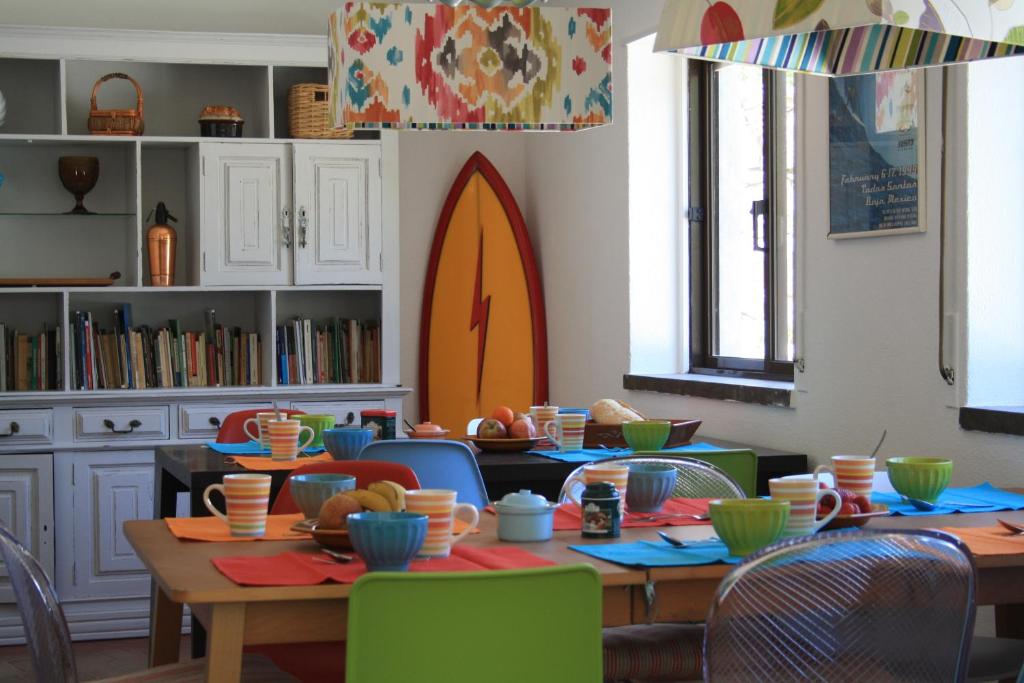 une salle à manger avec une table, des chaises et des bols. dans l'établissement Moby Dick Lodge, à Malveira da Serra