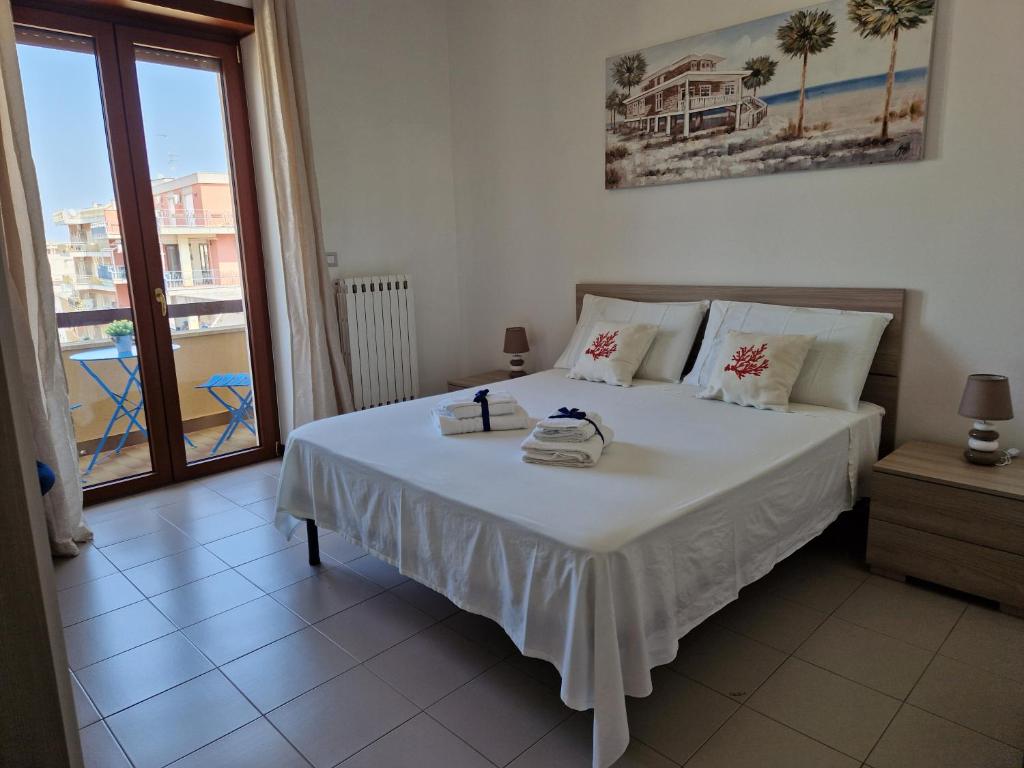 a bedroom with a large white bed and a balcony at Casa Rosetta in Lecce