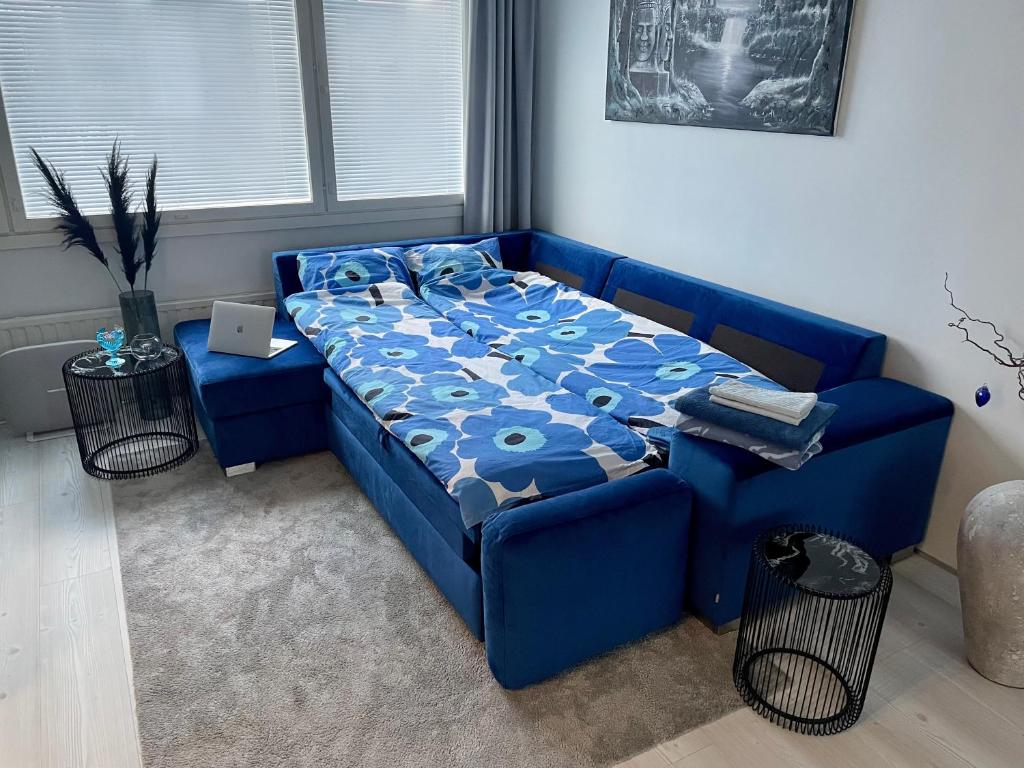 a blue couch in a room with a bed at Modern room in the city centre in Tampere