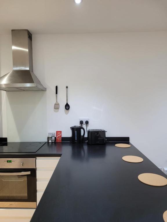 a kitchen with a black counter top with a stove at Amazing Canterbury 1 BR Flat in London CB54 in Croydon