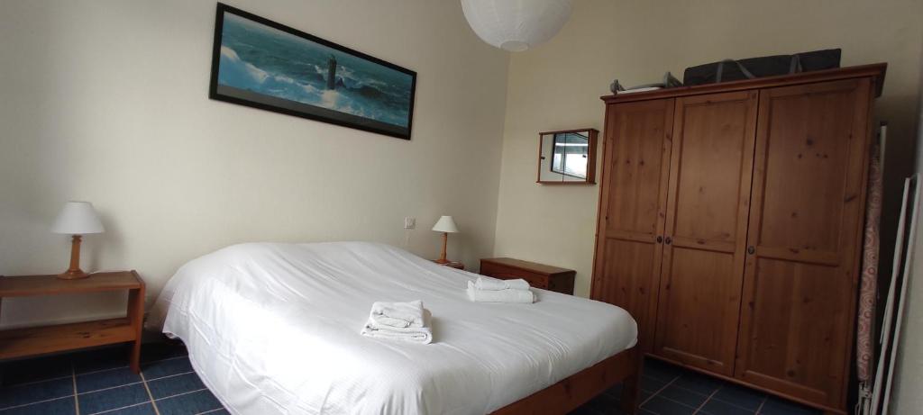 a bedroom with a white bed and a wooden cabinet at Eole in Wimereux