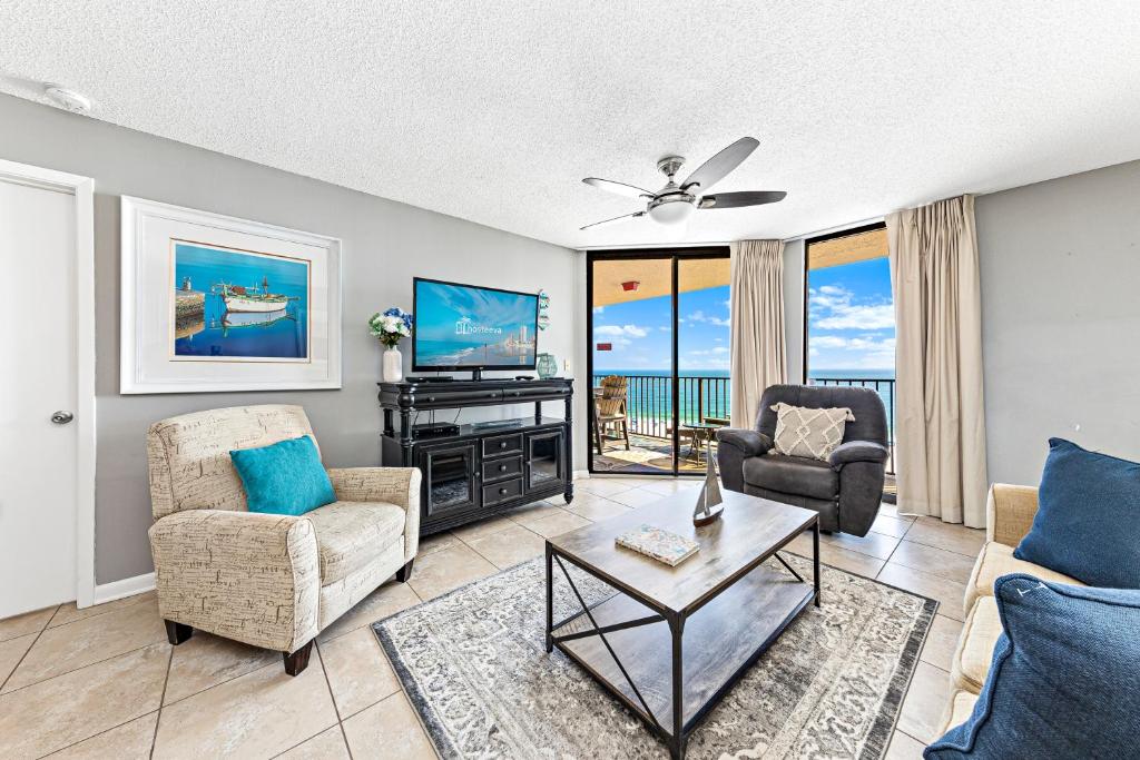 a living room with a couch and chairs and a tv at Phoenix East 904 in Orange Beach