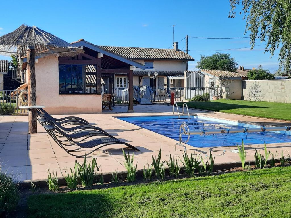 ein Swimmingpool mit Stühlen und ein Haus in der Unterkunft Maison au pied du Beaujolais in Saint-Georges-de-Reneins