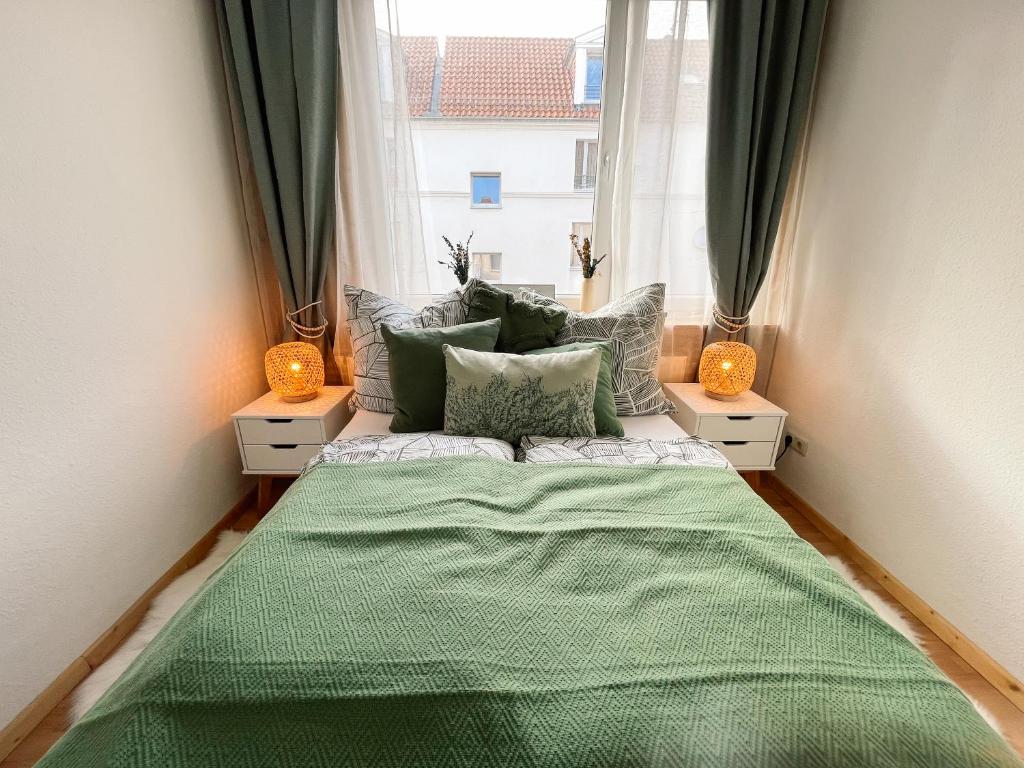 a bedroom with a green bed with two windows at Apartment mit großem Balkon in Hannover Nordstadt in Hannover