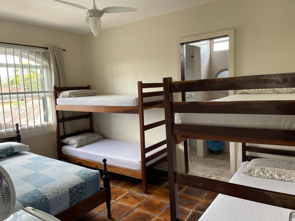 a room with three bunk beds and a window at Sunset Hostel Guarujá in Guarujá