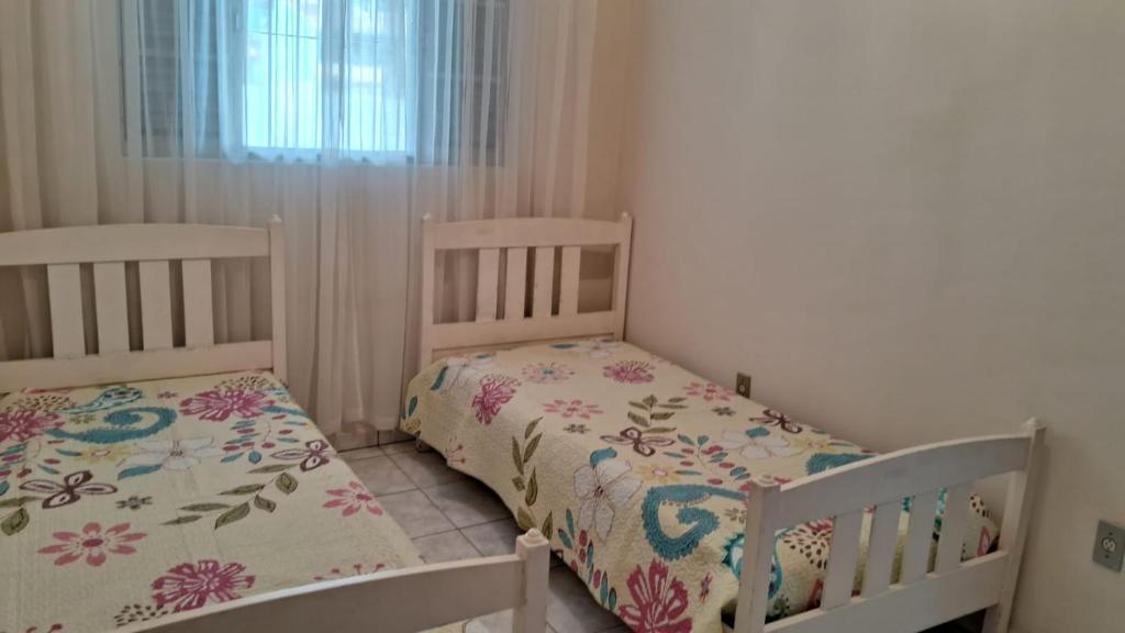 2 camas individuais num pequeno quarto com uma janela. em Casa Caraguatatuba Nelson em Caraguatatuba