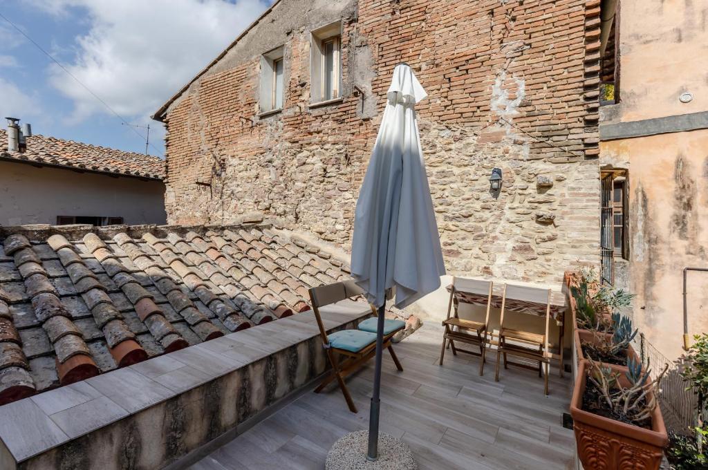 um guarda-sol e cadeiras num pátio com um edifício em Charming Terrace House in the heart of Perugia em Perugia