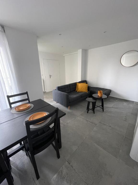 een woonkamer met een bank en een tafel en stoelen bij Appartement 4P, au pied de toute commodité in Créteil